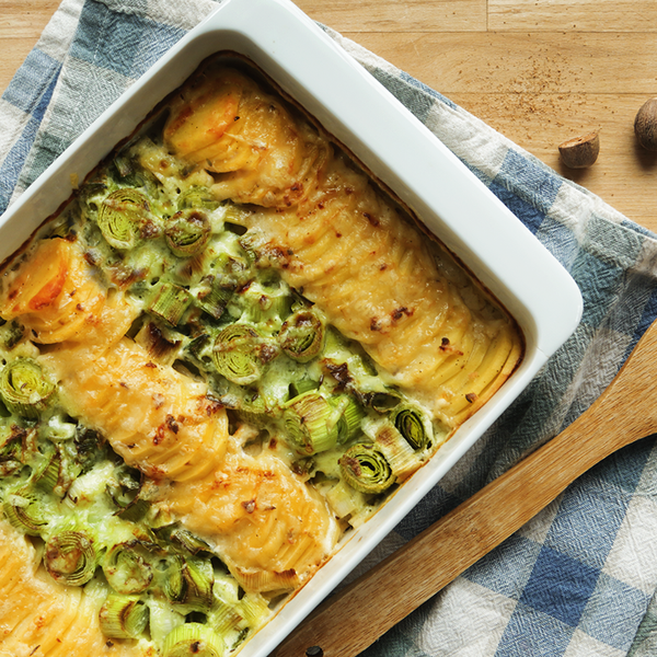 Lauch-Kartoffel-Gratin mit Holzlöffel auf einem Holztisch