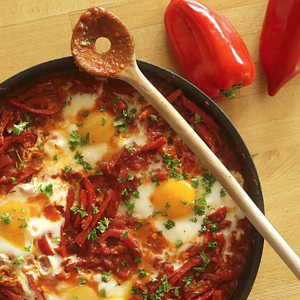 Shakshuka in einer Pfanne und Kochlöffel